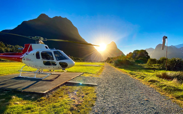Helicopter on the ground with blue skies and mountains in the background
