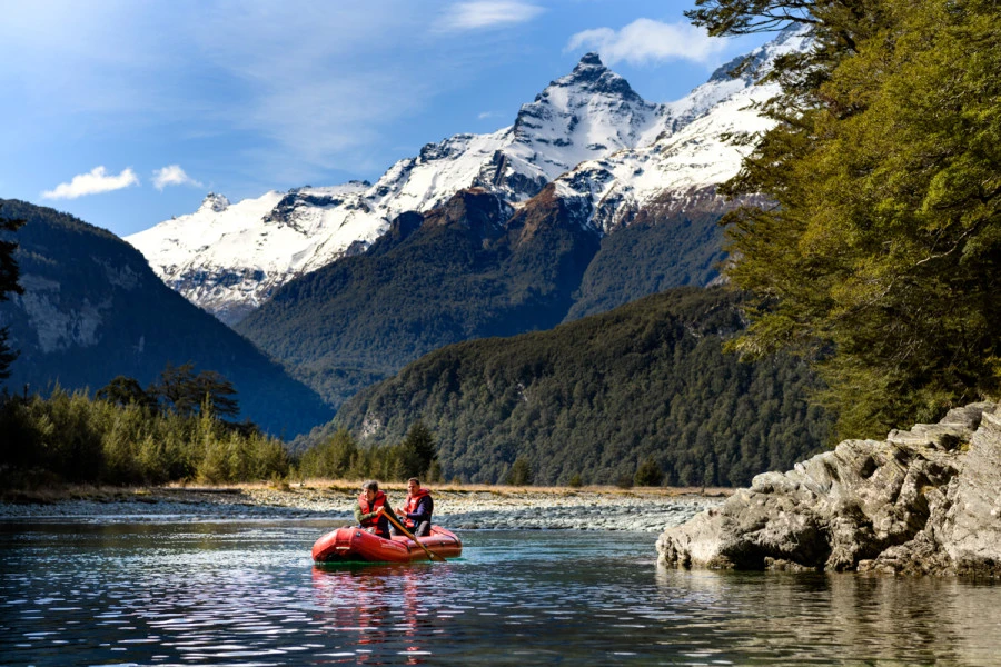 Funyak couple paddling on the river surrounded by mountains.and trees