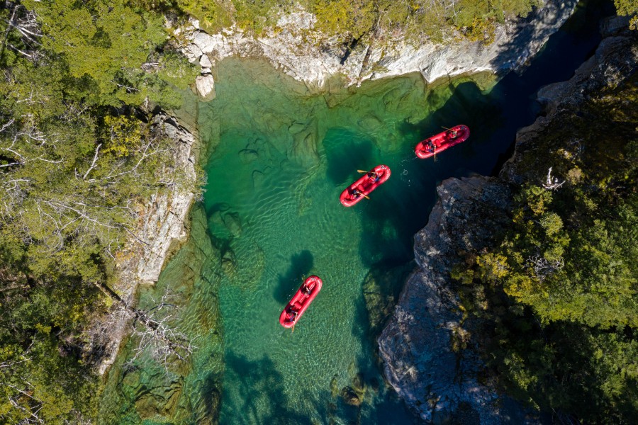 Three kayaks from above in clear river stream