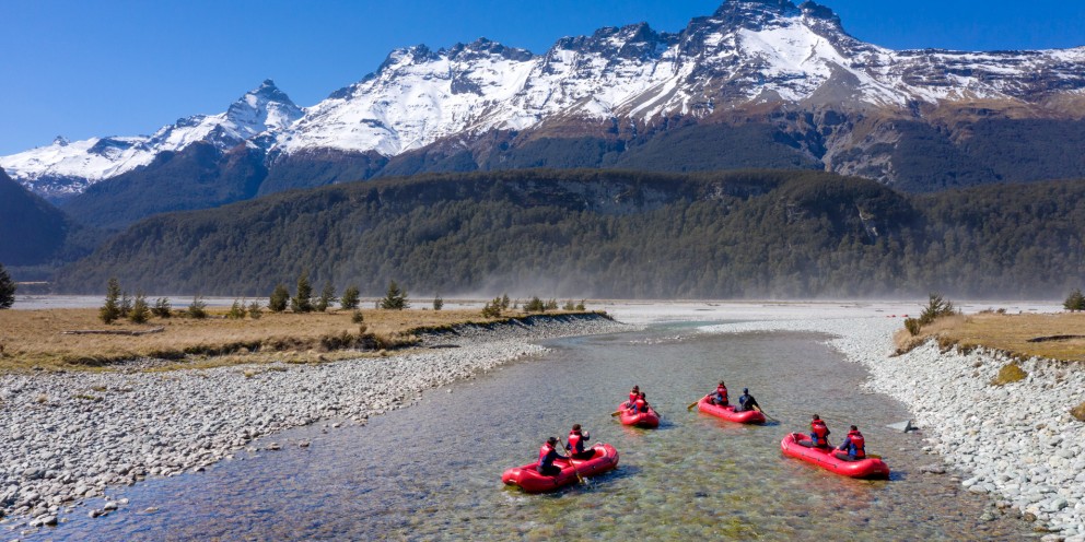 Group of kayaks in shallow river with alpine views