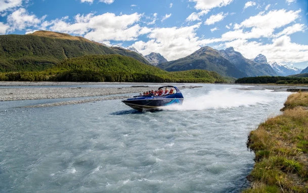 Jet boat speeding along the Dart River with water spraying behind.
