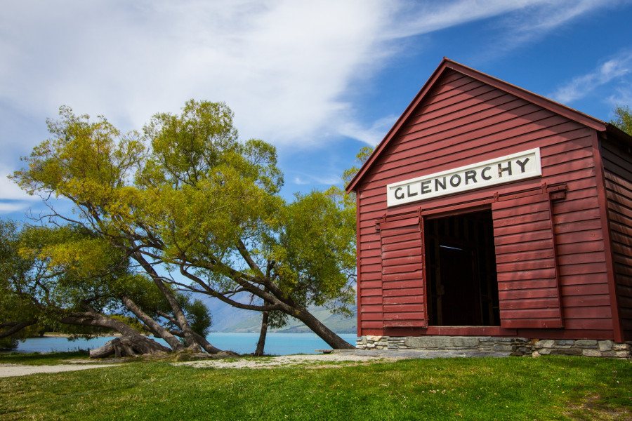 A red shed with glenorchy sign and tree next to Lake