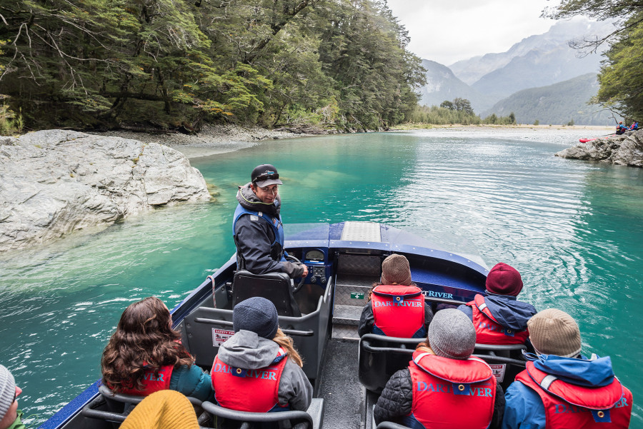 Jet boat driver talking to passengers looking to river ahead