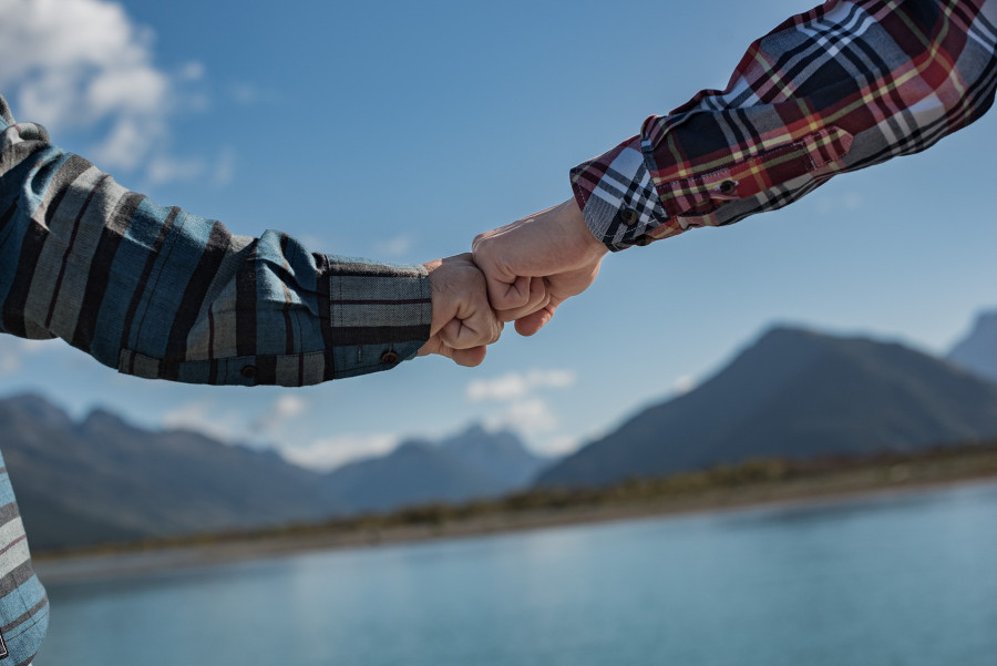 Two men joining knuckles with river and mountains in background