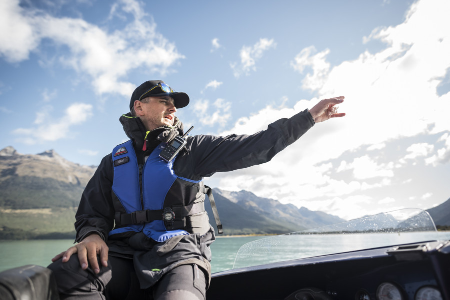 Jet boat guide pointing out views with river behind 