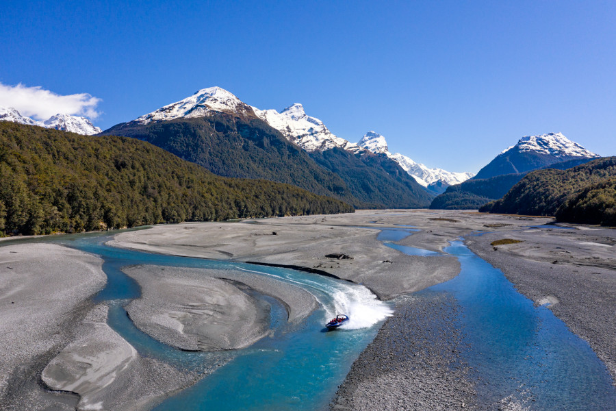 Jet boat travelling up crystal clear blue braided rivers 
